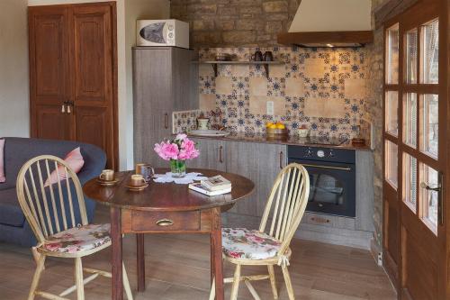 a kitchen with a wooden table and two chairs and a table with flowers at Cal Carulla in L'Astor