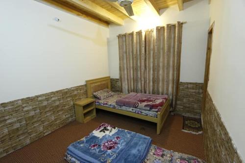 a room with two beds and a table in it at Baigs Paradise Guest House in Alīābād