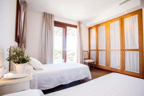 a hotel room with two beds and a window at Casa Santolina in Cala Saona