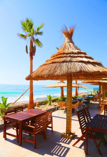 a beach with tables and chairs and a straw umbrella at Atlantica Parc in Taghazout