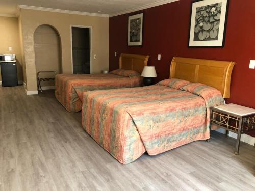duas camas num quarto de hotel com paredes vermelhas em Aqua Inn Motel em El Monte
