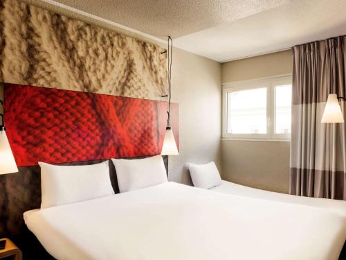 a hotel room with a bed and a painting on the wall at ibis Paris Place d’Italie 13ème in Paris