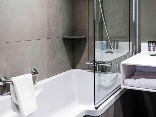 uma casa de banho com um chuveiro, uma banheira e um lavatório. em Novotel Paris 14 Porte d'Orléans em Paris