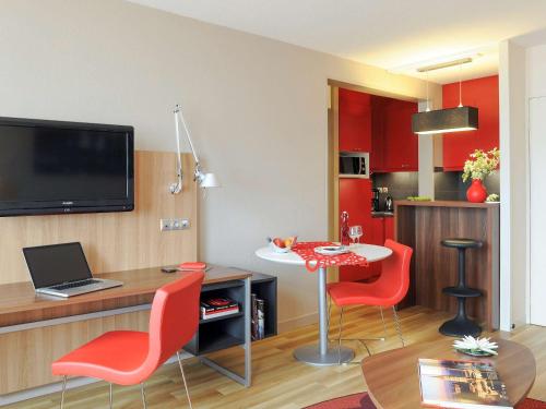 sala de estar con sillas rojas y mesa con ordenador portátil en Aparthotel Adagio Toulouse Centre Ramblas en Toulouse