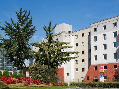 zwei Bäume in einem Park vor einem Gebäude in der Unterkunft ibis Paris Saint-Denis Stade Sud in Saint-Denis