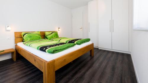 Una cama en una habitación con almohadas verdes. en Apartments Auriga en Saas-Fee