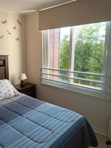 1 dormitorio con cama azul y ventana grande en Plaza Brintrup, en Puerto Varas