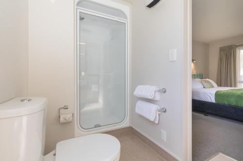 a bathroom with a shower and a toilet and a bed at Bella Vista Motel New Plymouth in New Plymouth