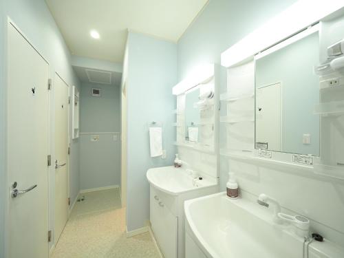 a white bathroom with a sink and a mirror at Family Tree Guest House in Sapporo