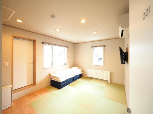 a small room with a bed and two windows at Family Tree Guest House in Sapporo