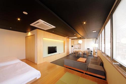 a bedroom with a bed and a couch and a tv at R Star Hostel Kyoto in Kyoto