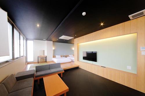 a bedroom with a bed and a tv and a couch at R Star Hostel Kyoto in Kyoto