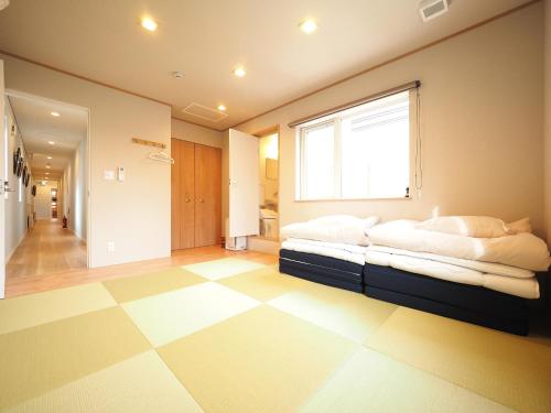 a bedroom with a bed with a window and a tiled floor at Family Tree Guest House in Sapporo