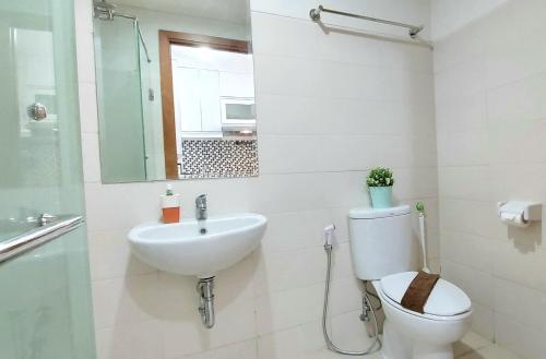 a bathroom with a toilet and a sink and a mirror at Woodland Park Residence-Relaxed and Friendly in Jakarta