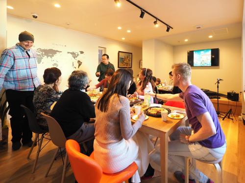 a group of people sitting around a table eating at Family Tree Guest House in Sapporo