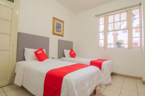 two beds in a room with red and white sheets at Hotel Imperial in Aguascalientes