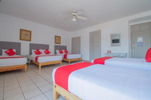 a bedroom with three beds with red and white sheets at Hotel Imperial in Aguascalientes