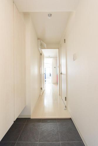 an empty hallway with white walls and a tile floor at COCOSTAY月光千日前3F - Cocostay Gekkou Sennichimae3F in Okayama