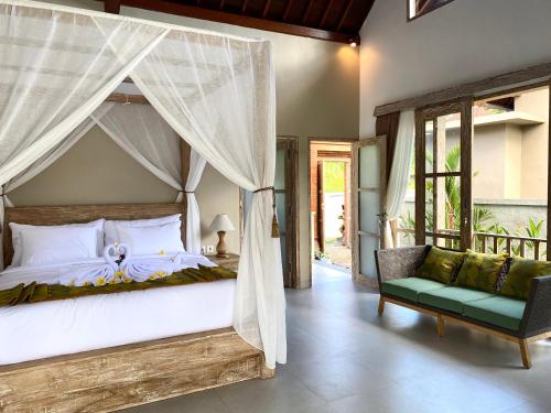 a bedroom with a canopy bed and a chair at Alamdhari Resort and Spa in Sidemen