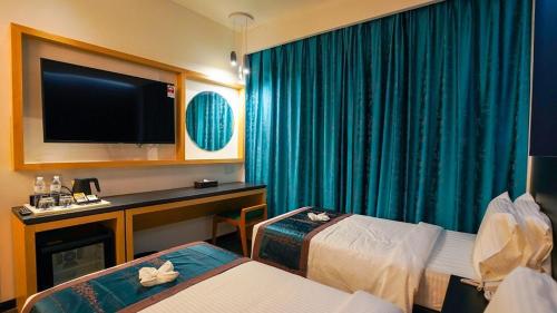 a hotel room with a flat screen tv and two beds at TSR Seafront Hotel in Port Dickson