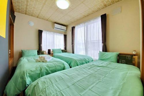 3 grüne Betten in einem Zimmer mit Fenster in der Unterkunft 旭川ファミリーハウスみんみん in Asahikawa