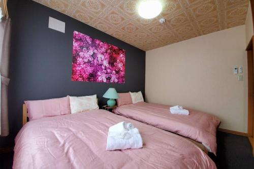 旭川市にある旭川ファミリーハウスみんみんの壁に絵画が描かれたベッドルームのピンクベッド2台