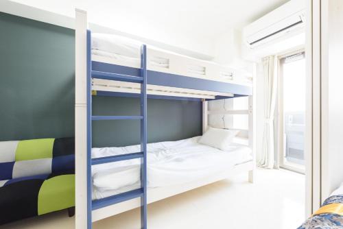 ein Schlafzimmer mit Etagenbetten in einem Zimmer mit Fenster in der Unterkunft Cocostay KO Residence Sennichimae5Fココステイ ケーオーレジデンス センニチマエ5F in Okayama