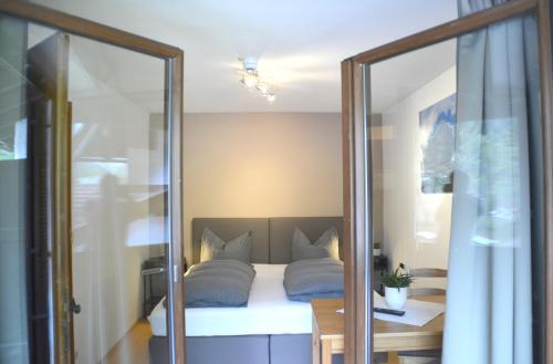 a bedroom with a bed with blue pillows and a mirror at Pension Almhof Baumgarten in Bad Reichenhall