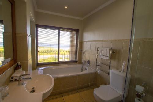 a bathroom with a tub and a toilet and a sink at On The Cliff Guest House in Hermanus