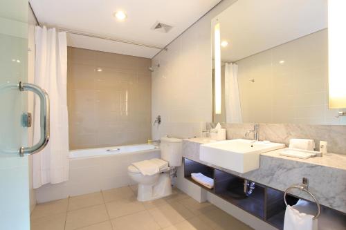 a bathroom with a sink and a toilet and a mirror at Swiss-Belinn Balikpapan in Balikpapan