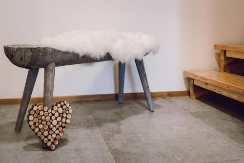 a wooden bench with a white furry seat and a table at Chalet Sunnseitn - auf der Turracher Höhe in Turracher Hohe