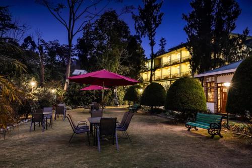 a group of chairs and tables with a bench and umbrella at Summit Barsana Resort & Spa in Kalimpong