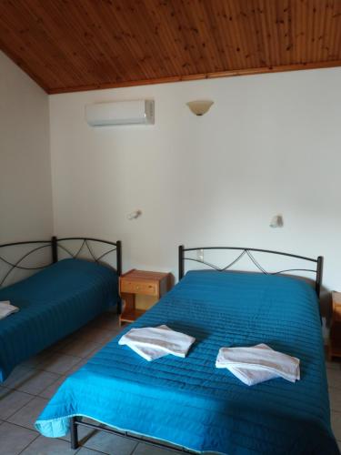 een slaapkamer met 2 bedden met blauwe lakens en een houten plafond bij Asimina's House in Skiathos-stad