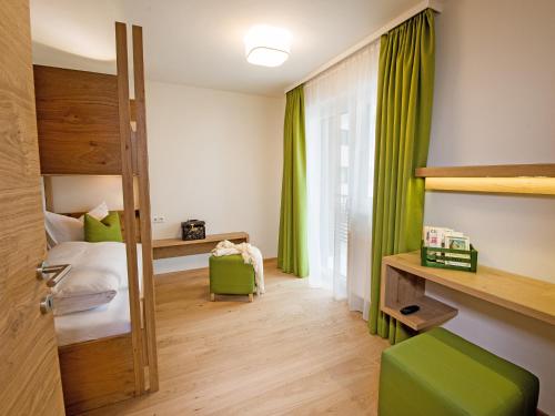 Schlafzimmer mit grünen Vorhängen, einem Bett und einem Schreibtisch in der Unterkunft Appartements Amarella in Bad Hofgastein