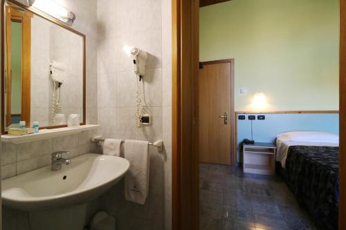 un bagno con lavandino, specchio e letto di Hotel Sabo' a Castel Maggiore
