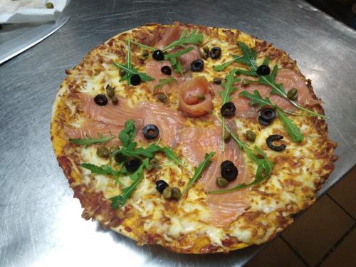 a pizza with ham and olives on a pan at Hotel Merino in Pas de la Casa