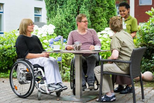 a group of people sitting at a table in a garden at Heidehotel Bad Bevensen in Bad Bevensen