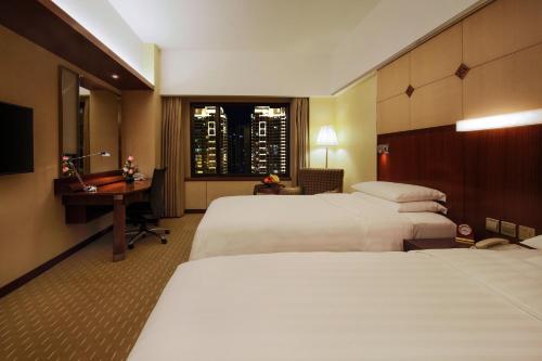 a hotel room with two beds and a desk and a window at Shangri-La Harbin in Harbin