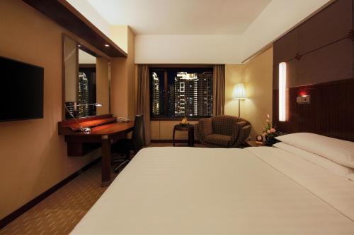 a hotel room with a bed and a desk and a window at Shangri-La Harbin in Harbin