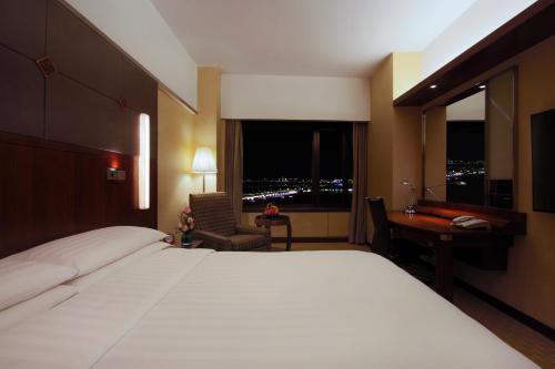 a hotel room with a bed and a desk and a window at Shangri-La Harbin in Harbin