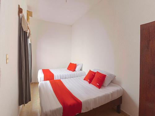 two beds in a room with red pillows on them at OYO Hotel Posada Los Faroles,Tabasco in Villahermosa