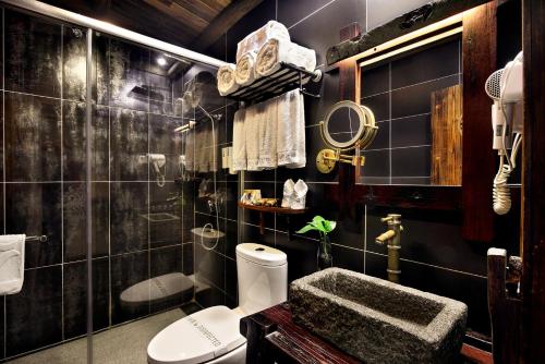 ein schwarz gefliestes Bad mit einem WC und einem Waschbecken in der Unterkunft Yangshuo Mountain Nest Boutique Hotel in Yangshuo