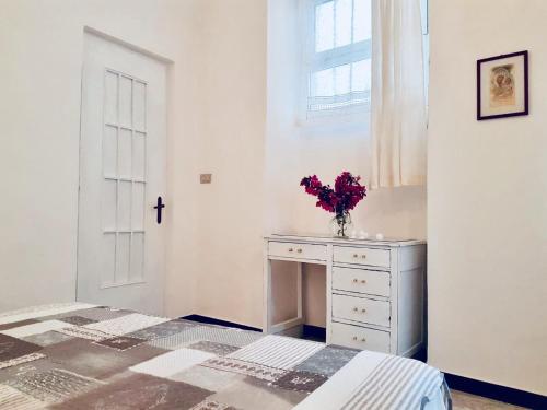 a white bedroom with a bed and a vase of flowers at Appartamento Stefano in Dolcedo
