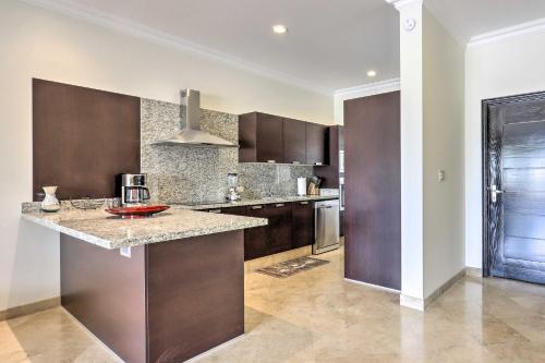 a kitchen with brown cabinets and a granite counter top at Walk to Beach Modern Cabo Condo with Balcony! in Cabo San Lucas