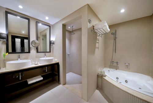 a bathroom with two sinks and a tub and a mirror at Voco - Riyadh by IHG in Riyadh