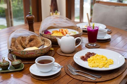 a wooden table topped with plates of food and cups of coffee at Villa Perle an Idyllic Luxury Retreat in Karangasem