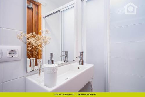 a white bathroom with a sink and a mirror at Solhabitat Coll de Mar in Calpe