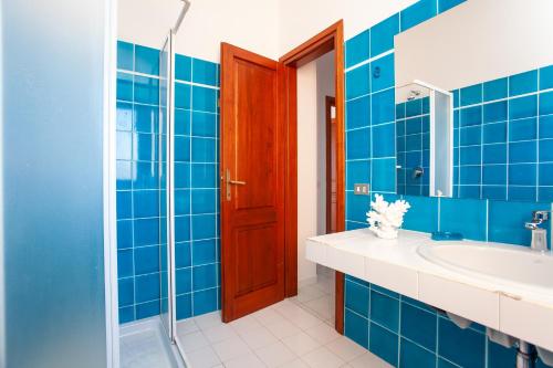 bagno piastrellato blu con lavandino e doccia di Residence Cinta 5 a San Teodoro