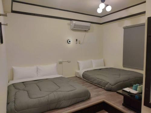 two beds sitting in a room with a tv at 綠島Gt大叔民宿 in Green Island