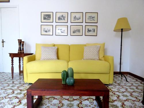 un sofá amarillo en una sala de estar con mesa en La terrazza, en Capri